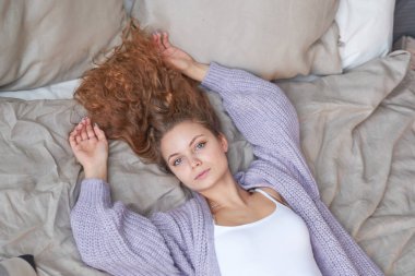 kızıl saçlı kız yatağa uzanır. sabah erken kalkmak, tembel hafta sonu.