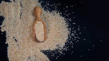 Siyah bir arka plan üzerinde beyaz Quinoa tohumları. Mutfak masası üst görünümünde kaşık quinoa. Sağlıklı ve diyet superfood ürün.