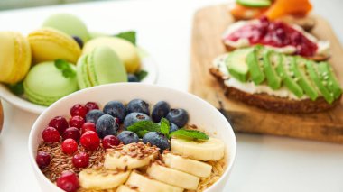 Kahvaltının üstü beyaz arka plan. Böğürtlenli yulaf ezmesi, tahta tepside tost, fındık, kahve.