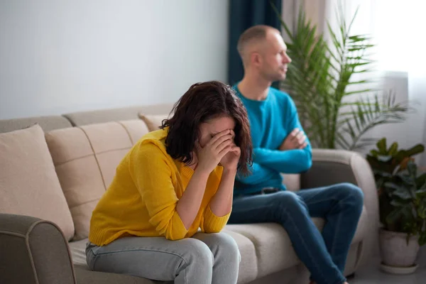 Esposa y marido tristes, pareja enojada en el dormitorio. concepto de pareja infeliz. usband y esposa están sentados en el sofá, mirando el uno al otro. marido no está listo para tener un diálogo — Foto de Stock