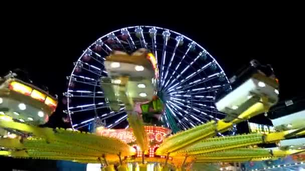 Passeio de roda gigante brilhantemente iluminado girando à noite em um carnaval, parque de diversões, parque temático, feira, parque de emoção. — Vídeo de Stock