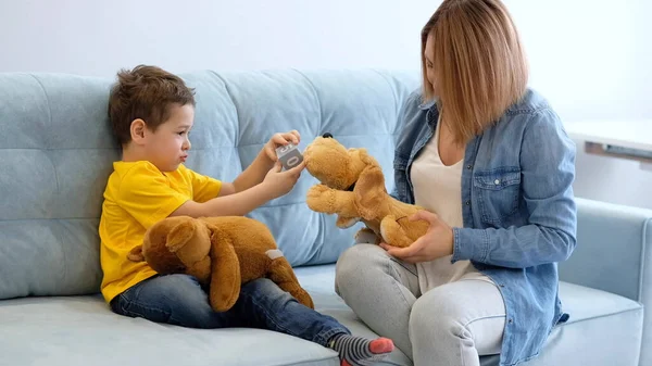 Utsikt över mamma som har roligt med bebisen. Mamma och son leker med leksaker på soffan. Ha kul tillsammans. Mamma försöker få kontakt med sin hyperaktiva son. — Stockfoto