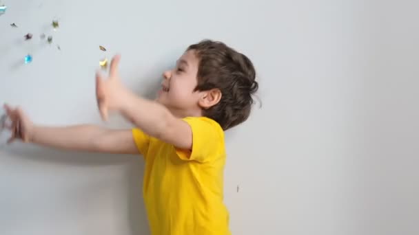 Criança feliz aniversário. Foto de encantador bonito fascinante menino agradável soprando confete em você para mostrar seu humor festivo com expressão facial emocional. Imagens de stock. Vídeo em câmara lenta. Fechar — Vídeo de Stock