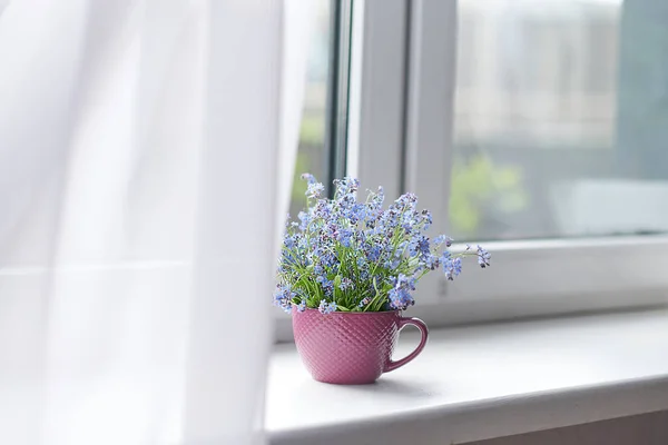 Spring bouquet of flowers and a cozy white plaid on the windowsill. white curtains cover part of the window — Stock Photo, Image