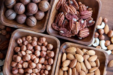 Koyu masada küçük tahta kasede farklı fındıklar. Fındıklı kaseler, üst manzara. Soyulmuş fındık. sağlıklı atıştırma konsepti