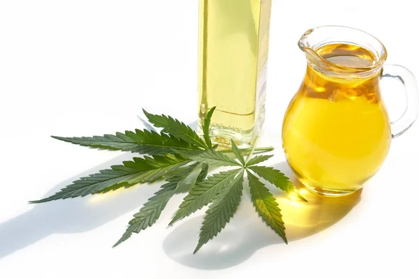 桌上的种子大麻，玻璃瓶里的油，白色背景下的大麻叶 — 图库照片