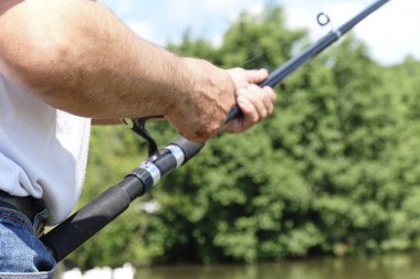 Nehirde balık avlıyorum. Nehir kıyısında elinde olta olan bir balıkçı. İnsan balıkçı bir balık yakalar. Balıkçılık, dönen makaralar, balıklar, Breg nehirleri. Kırsal kaçamak konsepti. Balıkçılık hakkında makale.