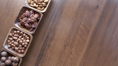 Masanın üstünde fındıklı ahşap kase. Sağlıklı yemek ve atıştırmalık. Ceviz, fıstık, badem, fındık ve fındık..