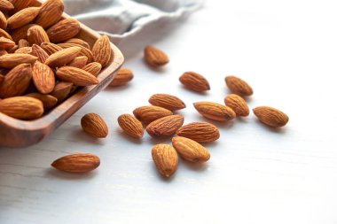 Beyaz ahşap bir masada, tahtadan bir kasede fındık.