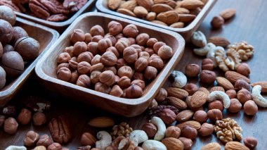 Masanın üstünde fındıklı ahşap kase. Sağlıklı yemek ve atıştırmalık. Ceviz, fıstık, badem, fındık ve fındık..