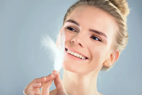 Retrato de chica atractiva con los ojos cerrados. hermosa mujer con una pluma blanca cerca de su cara. Concepto de cuidado de la piel de la cara y el cuerpo, piel brillante limpia fresca —  Fotos de Stock