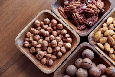 Masanın üstünde fındıklı ahşap kase. Sağlıklı yemek ve atıştırmalık. Ceviz, fıstık, badem, fındık ve fındık..