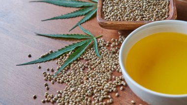 Masadaki kenevir tohumları, cam kavanozdaki yağ, beyaz arka plandaki kenevir yaprakları.