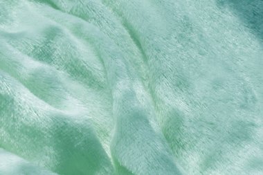 Pofuduk kumaşın yumuşak arka planı beyaz arka planda katlanır. Uzayı kopyala Düz yatıyordu. Leylak renginde sahte kürk kumaşında gevşek kıvrımlar var. Sıcak kış kıyafetlerinin ayrıntıları.