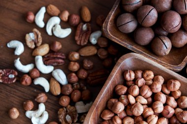 Masanın üstünde fındıklı ahşap kase. Sağlıklı yemek ve atıştırmalık. Ceviz, fıstık, badem, fındık ve fındık..