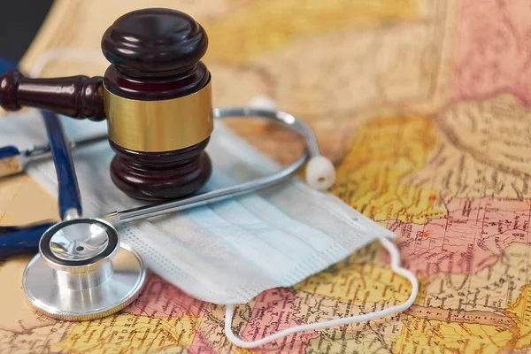 brown gavel and a medical stethoscope and a protective mask on a geographical map. symbol photo for bungling and medical error. Concept stay home and remote work.