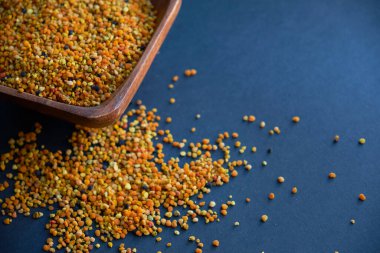 Tahta kaşıkta polen, sağlıklı besin maddeleri. Karanlık masa arka planı. İşçi bal arıları tarafından paketlenmiş çiçek poleni topağı ya da topağı