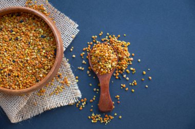 Tahta kaşıkta polen, sağlıklı besin maddeleri. Koyu tahta masa arkaplanı. İşçi bal arıları tarafından paketlenmiş çiçek poleni topağı ya da topağı