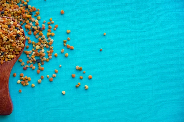 Pyłek pszczeli w drewnianej łyżce zdrowych suplementów diety. niebieskie tło stołu. kulka lub pelet pyłku kwiatowego zbieranego na polu przez pracownicze pszczoły miodne — Zdjęcie stockowe