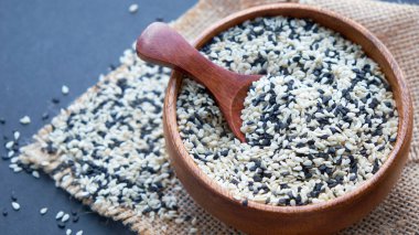 Organik doğal susam tohumları tahta kaşık. Kızarmış susam tohumu. Çiğ, bütün, işlenmemiş. Doğal ışık. Seçici odaklanma. Siyah bir arkaplana yaklaş. Üst manzara, düz yatış. metin için boşluk kopyala.