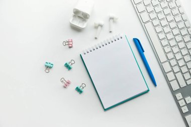 Klavyesi, not defteri, ofis bitkisi, düz dizüstü bilgisayarı olan şık, minimalist iş yeri. Beyaz arka plan. Boşluğu kopyala, düzleştir, üst görünüm, düzenle