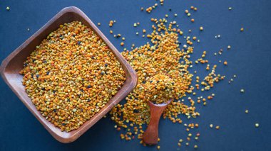 Tahta kaşıkta polen, sağlıklı besin maddeleri. Karanlık masa arka planı. İşçi bal arıları tarafından paketlenmiş çiçek poleni topağı ya da topağı