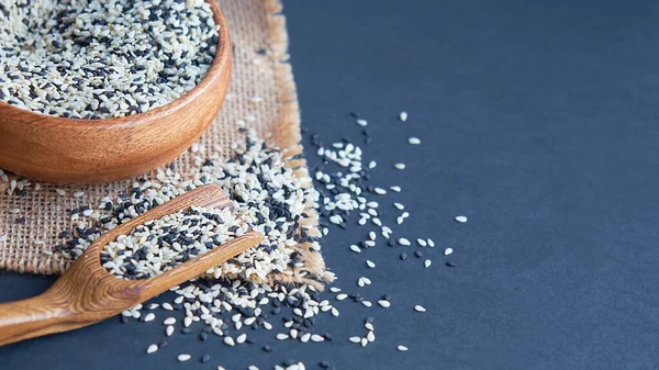 stock image Organic natural sesame seeds wooden spoon. toasted sesame seeds. Raw, whole, unprocessed. Natural light. Selective focus. Close up on a black background. Top view, flat lay. copy space for text.