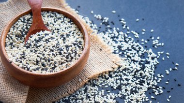 Organik doğal susam tohumları tahta kaşık. Kızarmış susam tohumu. Çiğ, bütün, işlenmemiş. Doğal ışık. Seçici odaklanma. Siyah bir arkaplana yaklaş. Üst manzara, düz yatış. metin için boşluk kopyala.