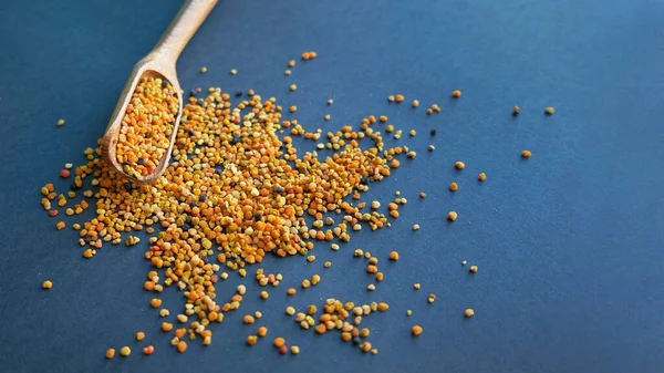 Bee pollen i en träsked hälsosamma kosttillskott. Närbild på en svart bakgrund. Ovanifrån, platt. kopieringsutrymme för text. — Stockfoto