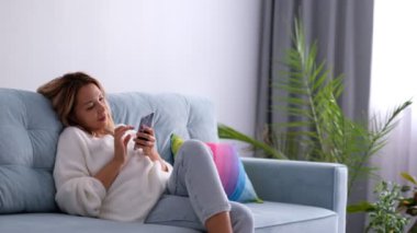 Huzurlu genç bayan oturma odasındaki kanepede dinleniyor. Sakin kadın serbest çalışan ellerini başının arkasına koyuyor, gözlerini kapatıyor ve evde uzak bir iş gününde ara veriyor, stresten uzak bir konsept..