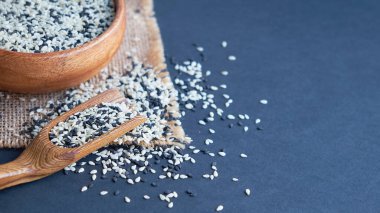 Organik doğal susam tohumları tahta kaşık. Kızarmış susam tohumu. Çiğ, bütün, işlenmemiş. Doğal ışık. Seçici odaklanma. Siyah bir arkaplana yaklaş. Üst manzara, düz yatış. metin için boşluk kopyala.