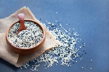 Organik doğal susam tohumları tahta kaşık. Kızarmış susam tohumu. Çiğ, bütün, işlenmemiş. Doğal ışık. Seçici odaklanma. Siyah bir arkaplana yaklaş. Üst manzara, düz yatış. metin için boşluk kopyala.