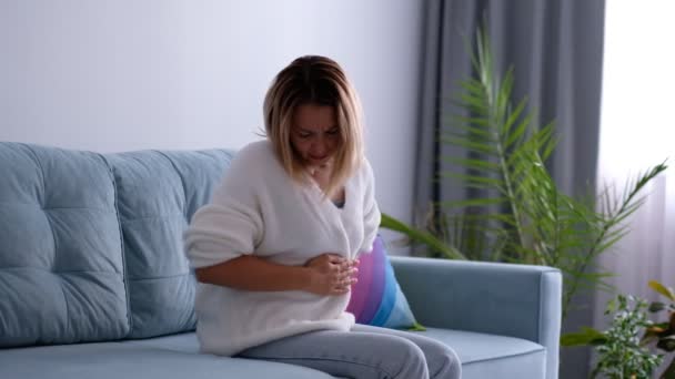 Mujer joven que experimenta dolor de estómago. personas, cuidado de la salud y concepto de problema. mujer que sufre de dolor de estómago. dolor intenso y calambres en la parte inferior del abdomen, menstruación. — Vídeo de stock