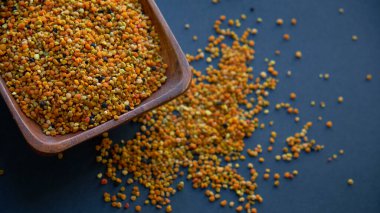 Tahta kaşıkta polen, sağlıklı besin maddeleri. Karanlık masa arka planı. İşçi bal arıları tarafından paketlenmiş çiçek poleni topağı ya da topağı