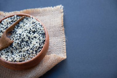 Organik doğal susam tohumları tahta kaşık. Kızarmış susam tohumu. Çiğ, bütün, işlenmemiş. Doğal ışık. Seçici odaklanma. Siyah bir arkaplana yaklaş. Üst manzara, düz yatış. metin için boşluk kopyala.