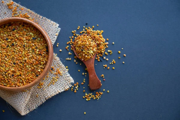 Tahta kaşıkta polen, sağlıklı besin maddeleri. Siyah bir arkaplana yaklaş. Üst manzara, düz yatış. metin için boşluk kopyala.