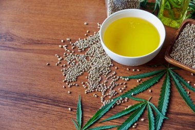 Masadaki kenevir tohumları, cam kavanozdaki yağ, beyaz arka plandaki kenevir yaprakları.