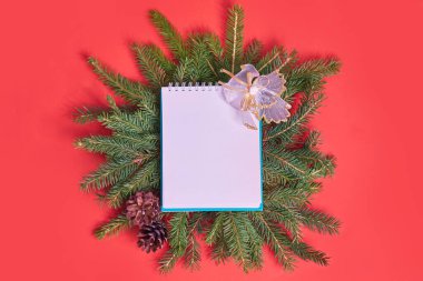 Kırmızı arka planda Noel ağacına yakın çekim. Kağıt kartla Noel ağacı dallarından yapılmış yaratıcı bir düzen. Noel ve Yeni Yıl tatili geçmişi. Düz konum, üst görünüm, kopyalama alanı