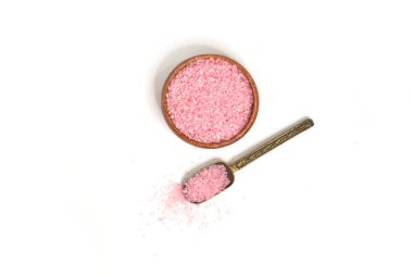 Kepçedeki pembe tuz ve beyaz arka planda izole edilmiş ahşap bir kase. seçici odak ya da bulanık.