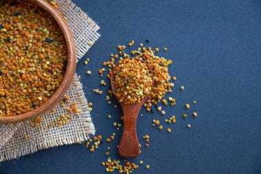 Tahta kaşıkta polen, sağlıklı besin maddeleri. Siyah bir arkaplana yaklaş. Üst manzara, düz yatış. metin için boşluk kopyala.