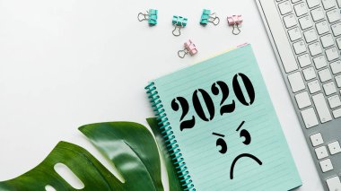Hüzünlü emojili not defteri olan bir masa. Hüzünlü bir yıl konsepti. 2020 ve üzgün bir yüz. 2020 korkunç yıl konsepti. Kapat..