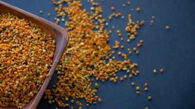 Tahta kaşıkta polen, sağlıklı besin maddeleri. Karanlık masa arka planı. İşçi bal arıları tarafından paketlenmiş çiçek poleni topağı ya da topağı