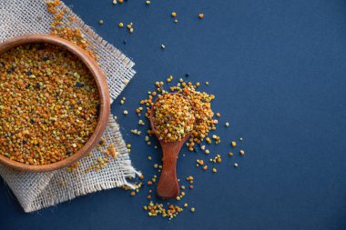 Tahta kaşıkta polen, sağlıklı besin maddeleri. Siyah bir arkaplana yaklaş. Üst manzara, düz yatış. metin için boşluk kopyala.