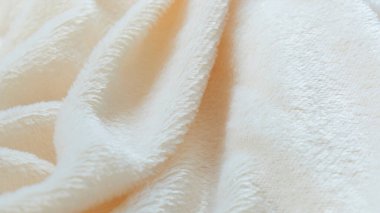 Pofuduk kumaşın yumuşak arka planı beyaz arka planda katlanır. Uzayı kopyala Düz yatıyordu. Leylak renginde sahte kürk kumaşında gevşek kıvrımlar var. Sıcak kış kıyafetlerinin ayrıntıları.