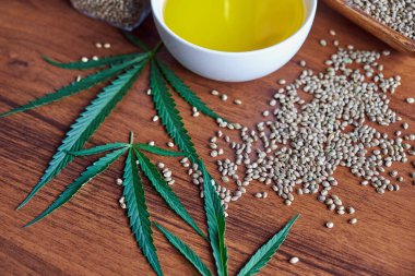 Masadaki kenevir tohumları, cam kavanozdaki yağ, beyaz arka plandaki kenevir yaprakları.