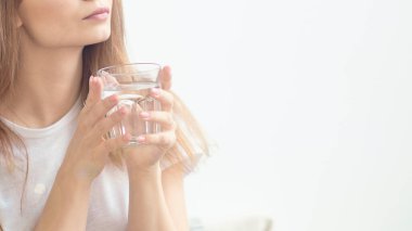 Tanınmayacak kadar güzel genç bir kız bardaktan su içiyor..