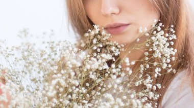 Beyaz kadın çiçek buketinin tadını çıkarıyor. Genç, tanınmayan bir kadın. Yakın görüş..