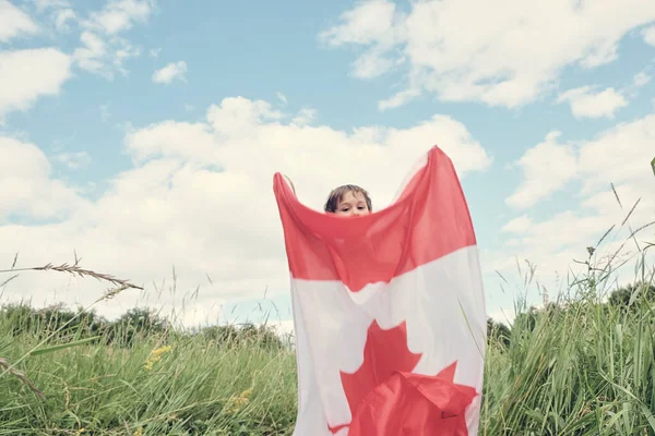 Menino feliz acenando com a bandeira do Canadá enquanto corre — Fotografia de Stock