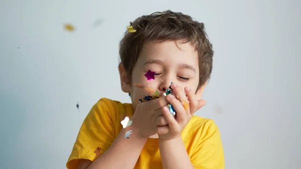 Happy birthday child. Photo of charming cute fascinating nice little boy blowing confetti at you to show her festive mood with emotional face expression. — Stock Photo, Image