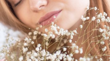 Beyaz kadın çiçek buketinin tadını çıkarıyor. Genç, tanınmayan bir kadın. Yakın görüş..